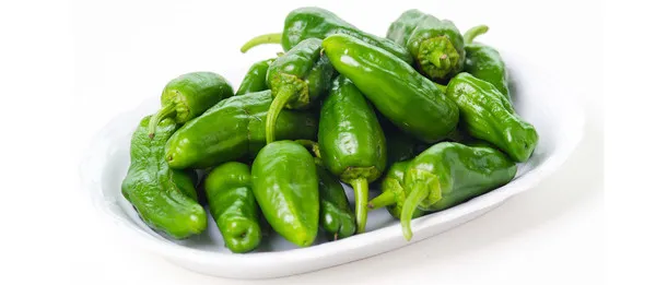 Pimientos verdes Cortella frescos en un plato blanco sobre fondo claro