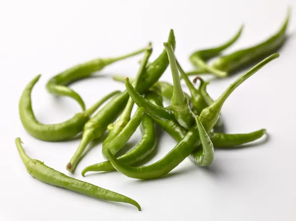 Varios chiles verdes largos y curvos de piparra sobre fondo blanco